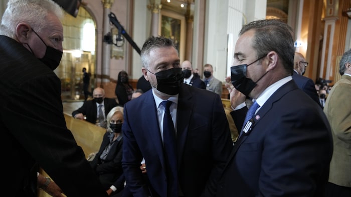 Les trois hommes discutent à l'intérieur de la cathédrale.