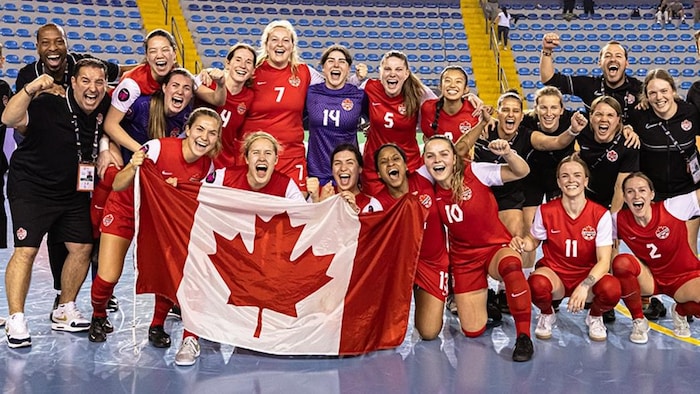 Une équipe de futsal célèbre une victoire en montrant le drapeau canadien.
