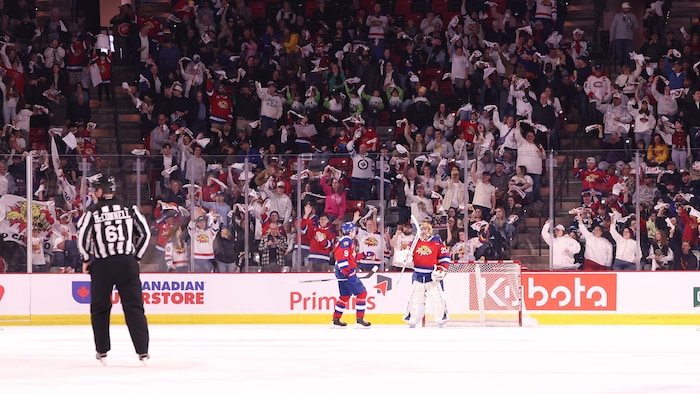 Joueur donnant la main à son gardien de but. Derrière, la foule applaudit.