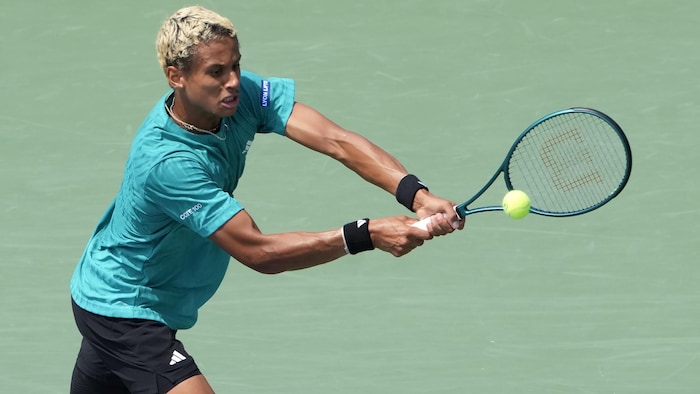 Un joueur de tennis frappe un revers.