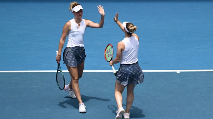 Deux joueuses de tennis se félicitent en se tapant dans la main.