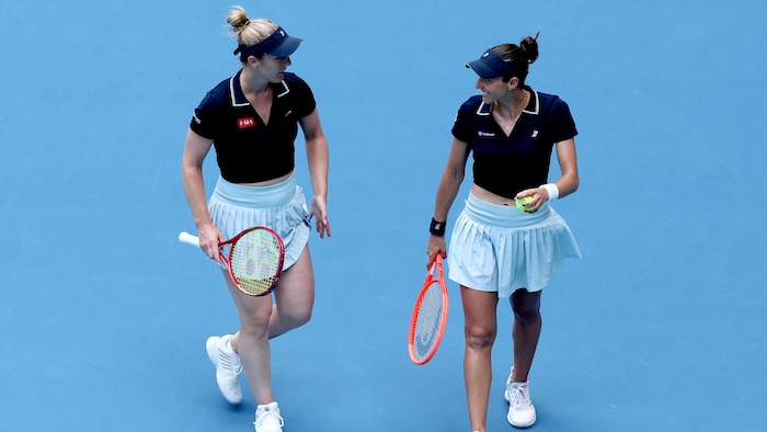 Deux joueuses de tennis se parlent sur le terrain.