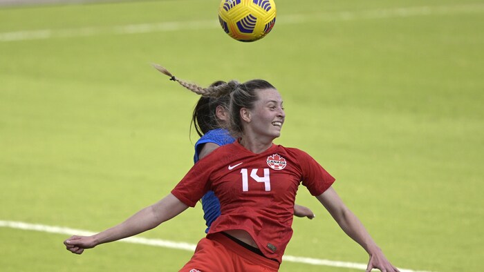 Deux joueuses de soccer tentent de frapper le ballon de la tête. 