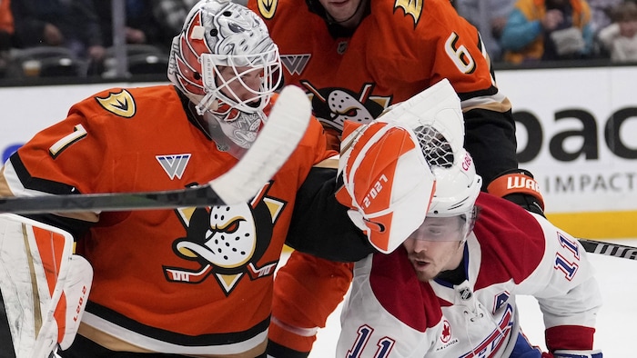 Un gardien de hockey met son gant au visage d'un joueur adverse. 