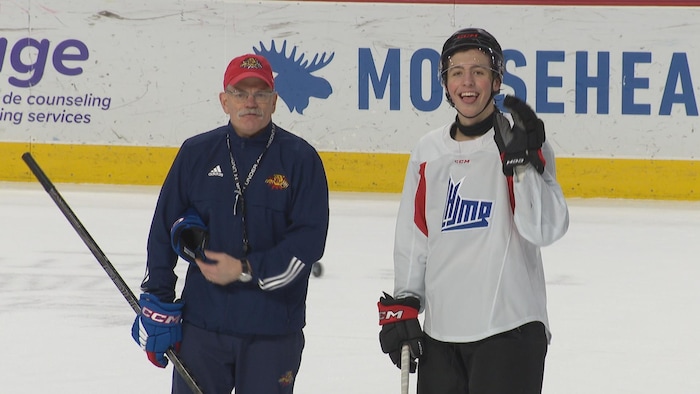 Homme avec une casquette est à côté d'un joueur de hockey.