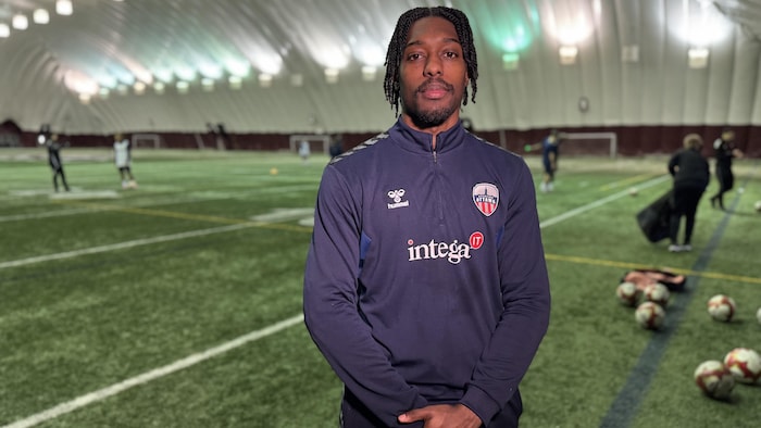 Un gardien de but au soccer prend la pose pour la caméra sur un terrain.