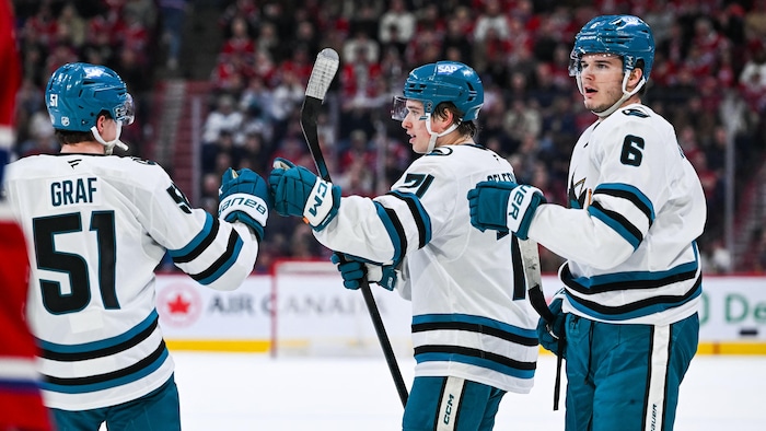 Trois joueurs célèbrent un but.