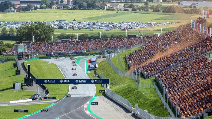 Des voitures de formule 1 roulent sur le circuit de Spielberg, en Autriche, devant des gradins bondés de supporteurs.