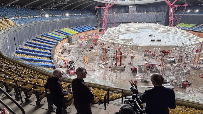 Il se tient debout dans les gradins et contemple l'intérieur du stade en rénovation.