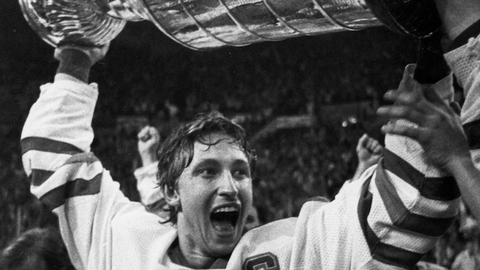 Photo en noir et blanc où on voit Wayne Gretzky soulever la coupe Stanley.