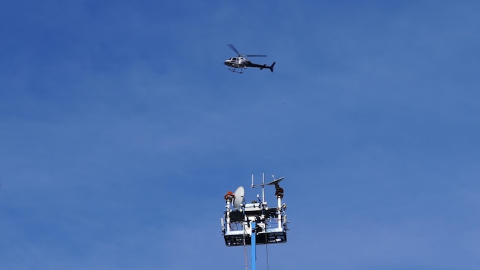 Un hélicoptère surplombe une antenne de diffusion.