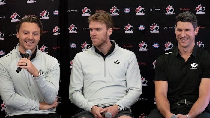 Trois hockeyeurs répondent aux questions des journalistes lors d'une conférence de presse.