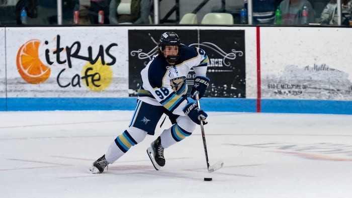 Un jeune hockeyeur patine avec la rondelle.