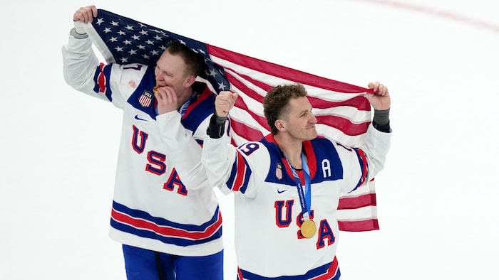 Deux hockeyeurs américains célèbrent avec le drapeau des États-Unis et leur médaille d'or olympique.