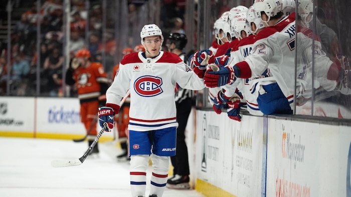 Un hockeyeur donne la main à ses coéquipiers au banc.