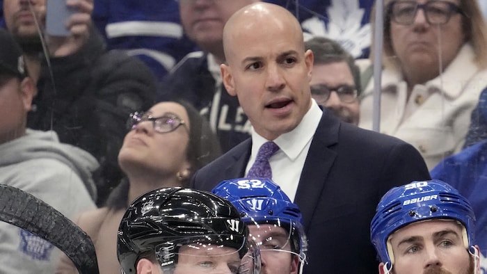 Un entraîneur derrière le banc d'une équipe de hockey.