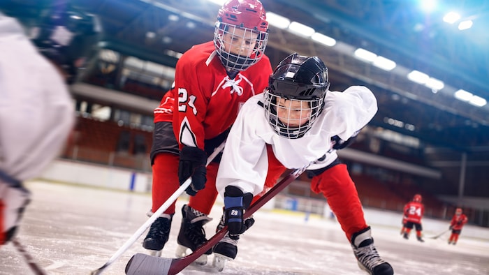 Deux jeunes garçons qui tentent de contrôler une rondelle de hockey.