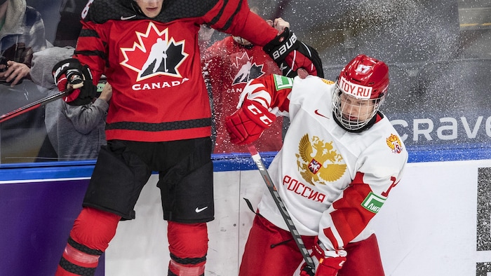 Deux joueurs de hockey tentent de prendre possession de la rondelle.