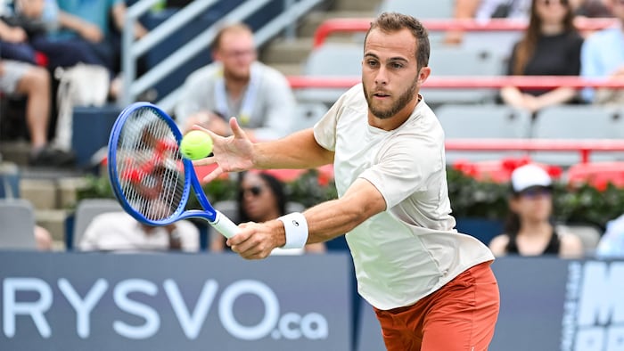 Un joueur de tennis frappe un revers. 