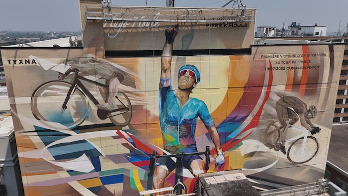Plan large sur la murale, qui illustre Hugo Houle qui lève le bras droit en l'air pour célébrer sa victoire