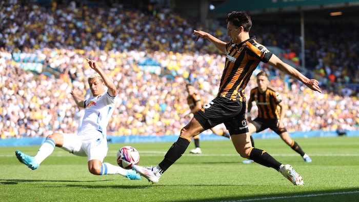 Un joueur de soccer tente une passe dans un stade bondé.