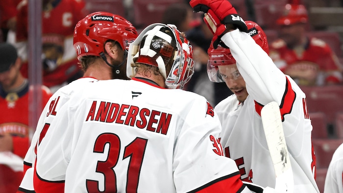 Trois joueurs de hockey célèbrent leur victoire. 