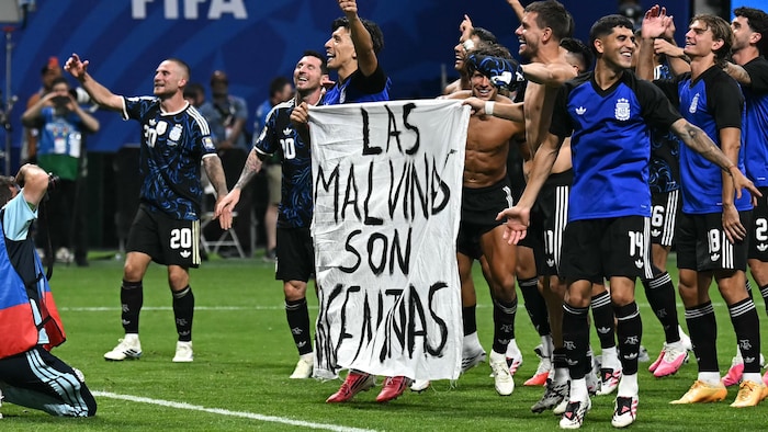 Des joueurs de soccer argentins tiennent une banderole où il est écrit « les Malouines sont argentines ».