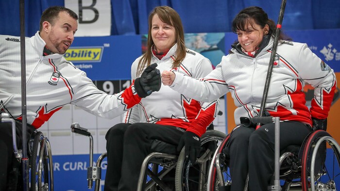 Une athlète de curling paralympique célèbre ses performances avec ses coéquipiers. 