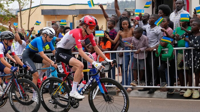 Elle mène le peloton, entourée de partisans portant des drapeaux du Rwanda.