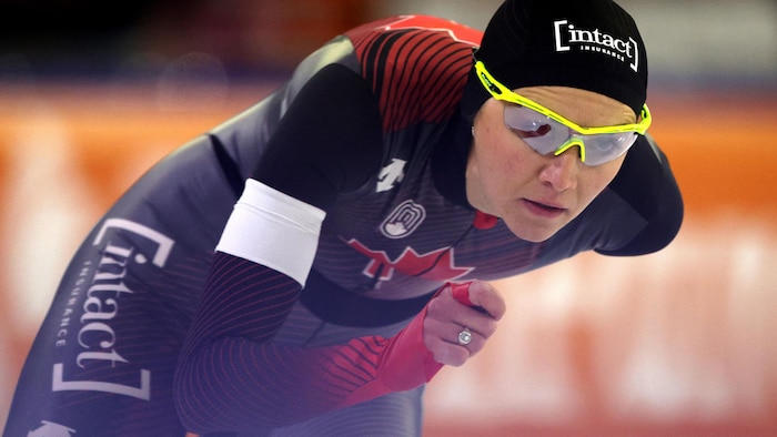 Elle est en pleine course de patinage de vitesse.