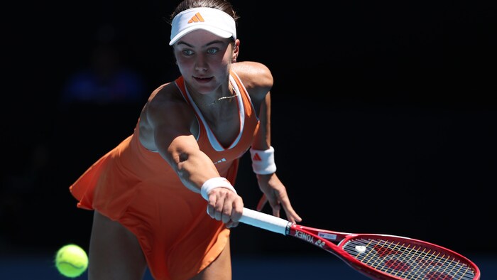 Une joueuse de tennis regarde la balle en préparant un coup du revers.