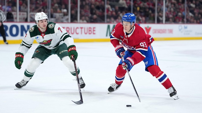 Un joueur de hockey avec la rondelle face à un adversaire.