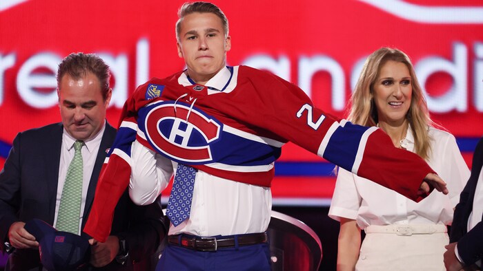 Il enfile un chandail de hockey rouge. 