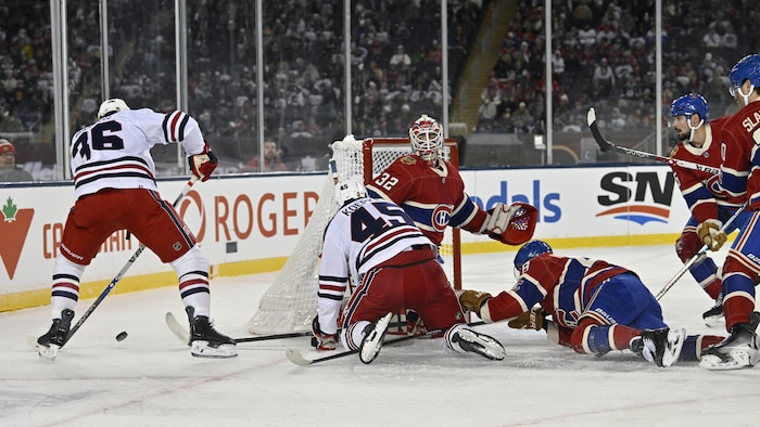Des joueurs de hockey autour d'un filet et d'un gardien.