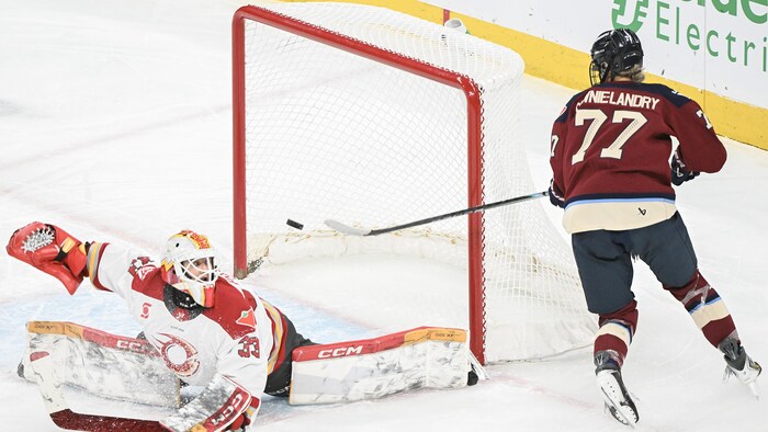 Une joueuse de hockey défait la gardienne adverse et passe près de marquer un but.