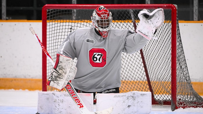 Un gardien de but de hockey effectue un arrêt avec sa mitaine.