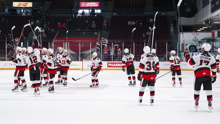 Des joueurs de hockey célèbrent une victoire en saluant la foule.