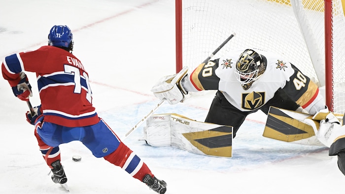 Un joueur de hockey avec la rondelle devant un gardien.