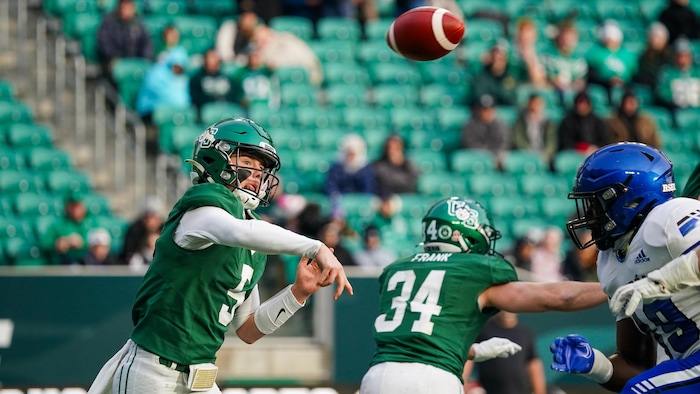 Un joueur de football lance une passe devant un adversaire.