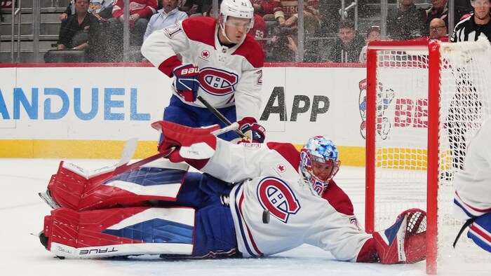 Un gardien de but est allongé devant son filet et un coéquipier.