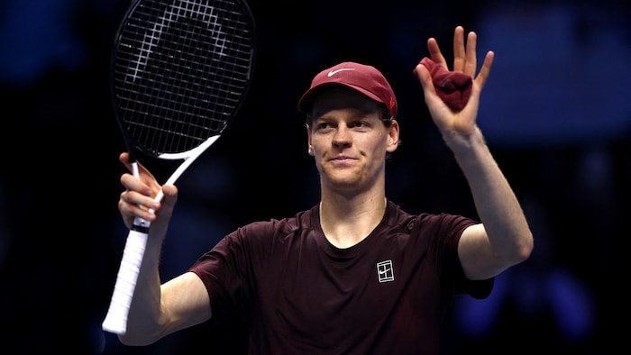 Un joueur de tennis salue la foule en levant les bras.