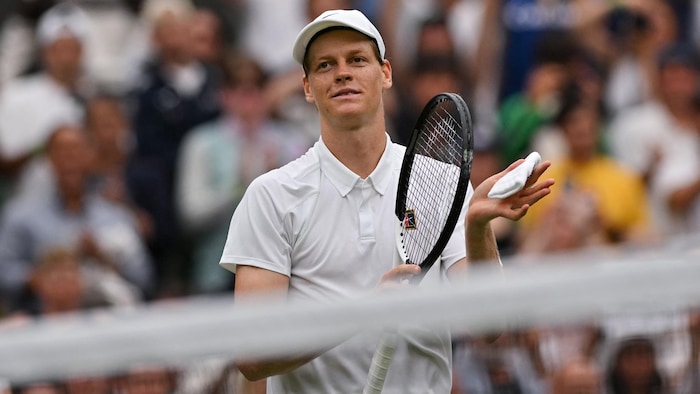 Un joueur de tennis applaudit avec sa raquette.