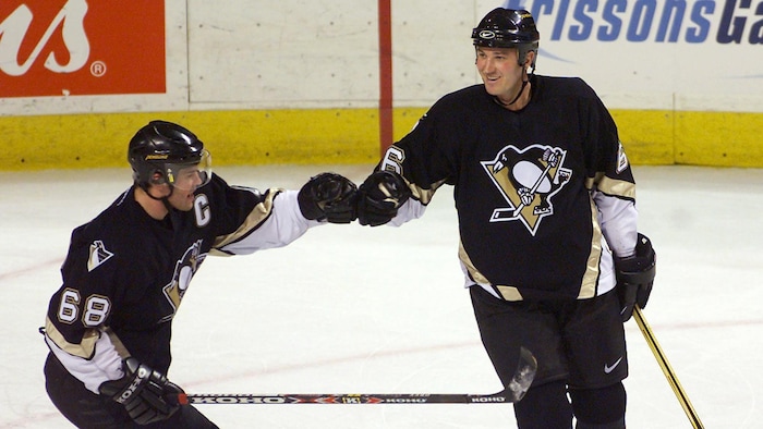 Deux joueurs de hockey se tapent la main avec leurs gants.