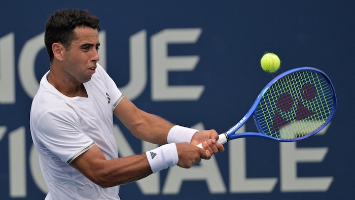 Un joueur de tennis frappe un revers. 