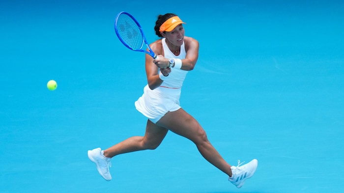 Une joueuse de tennis frappe une balle en courant.