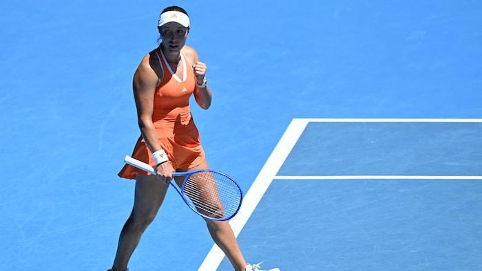Une joueuse de tennis marche sur le court en serrant le poing. 