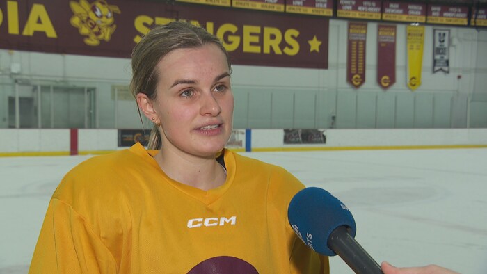 Une hockeyeuse en jaune répond aux questions d'un journaliste.