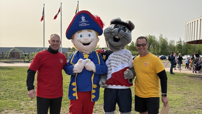 Deux organisateurs de la course au flambeau avec deux mascottes.