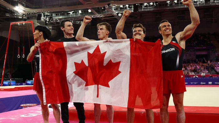 Des athlètes célèbrent leur victoire en tenant un drapeau canadien.