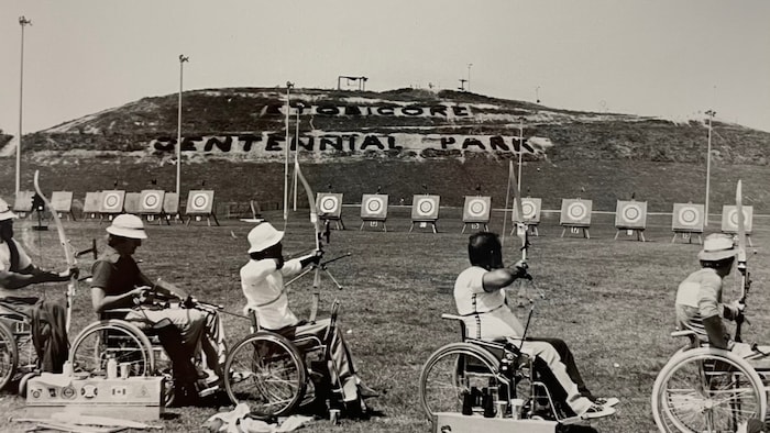 Des athlètes en fauteuil roulant effectuent des lancers, à quelques mètres de cibles placées dans un parc.